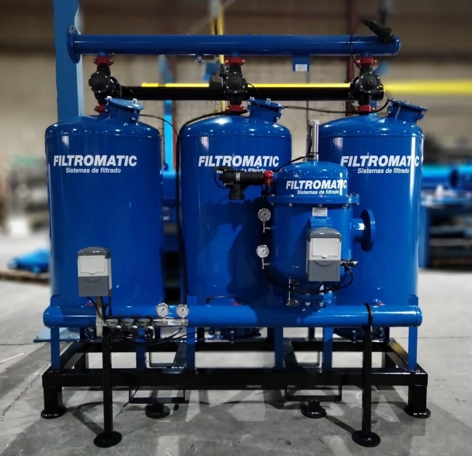 Industrial filtration system with three blue tanks labeled 'Filtromatic' and various control valves and gauges.